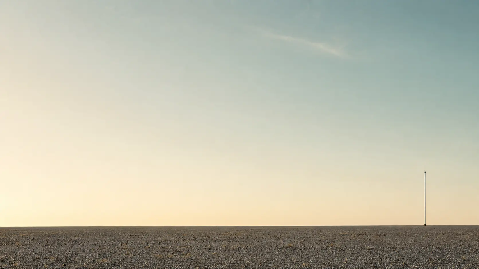 A single distant signal mast on a vast Namibian gravel horizon