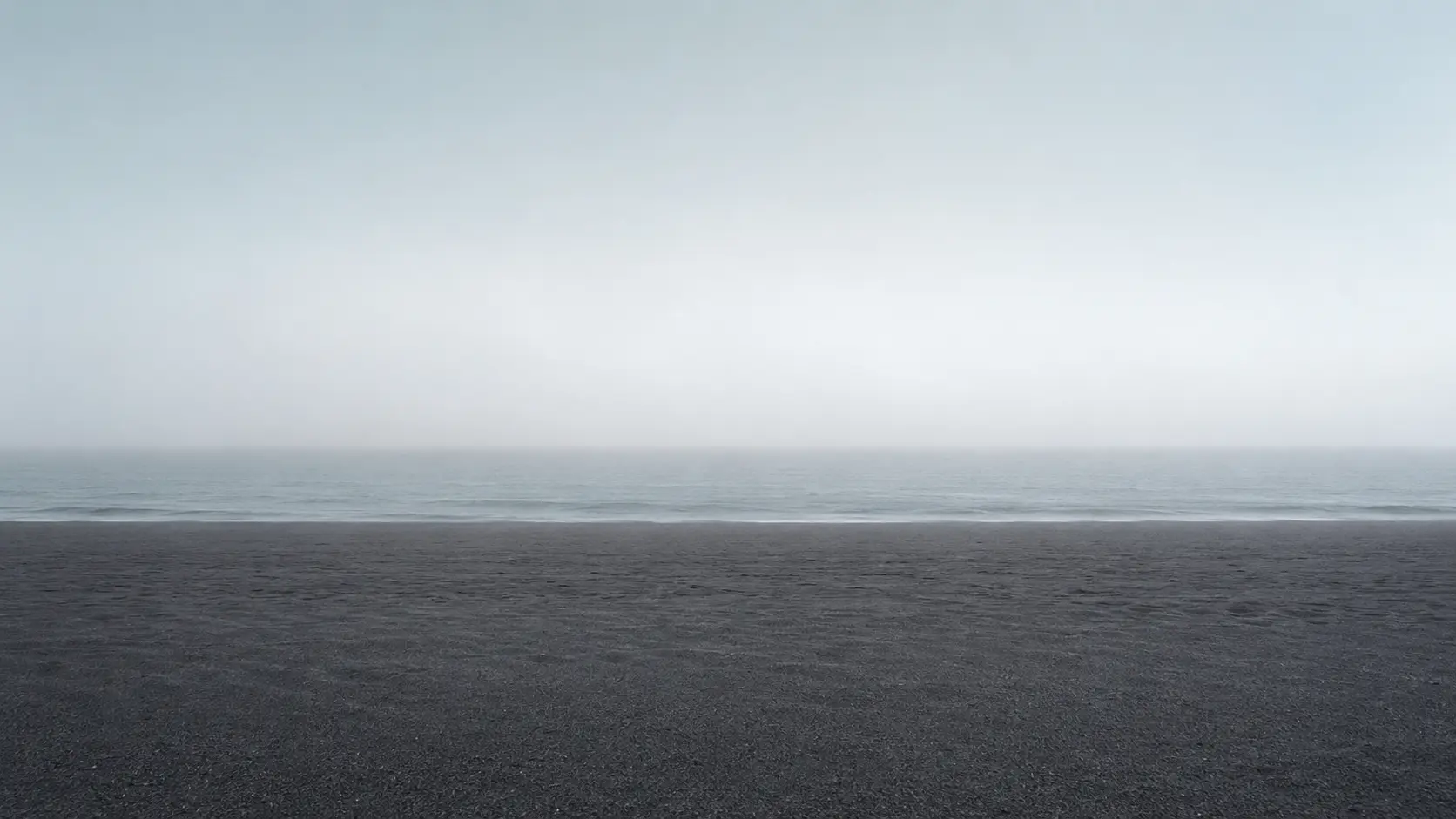 A quiet fog horizon where the Atlantic meets a dark Skeleton Coast beach