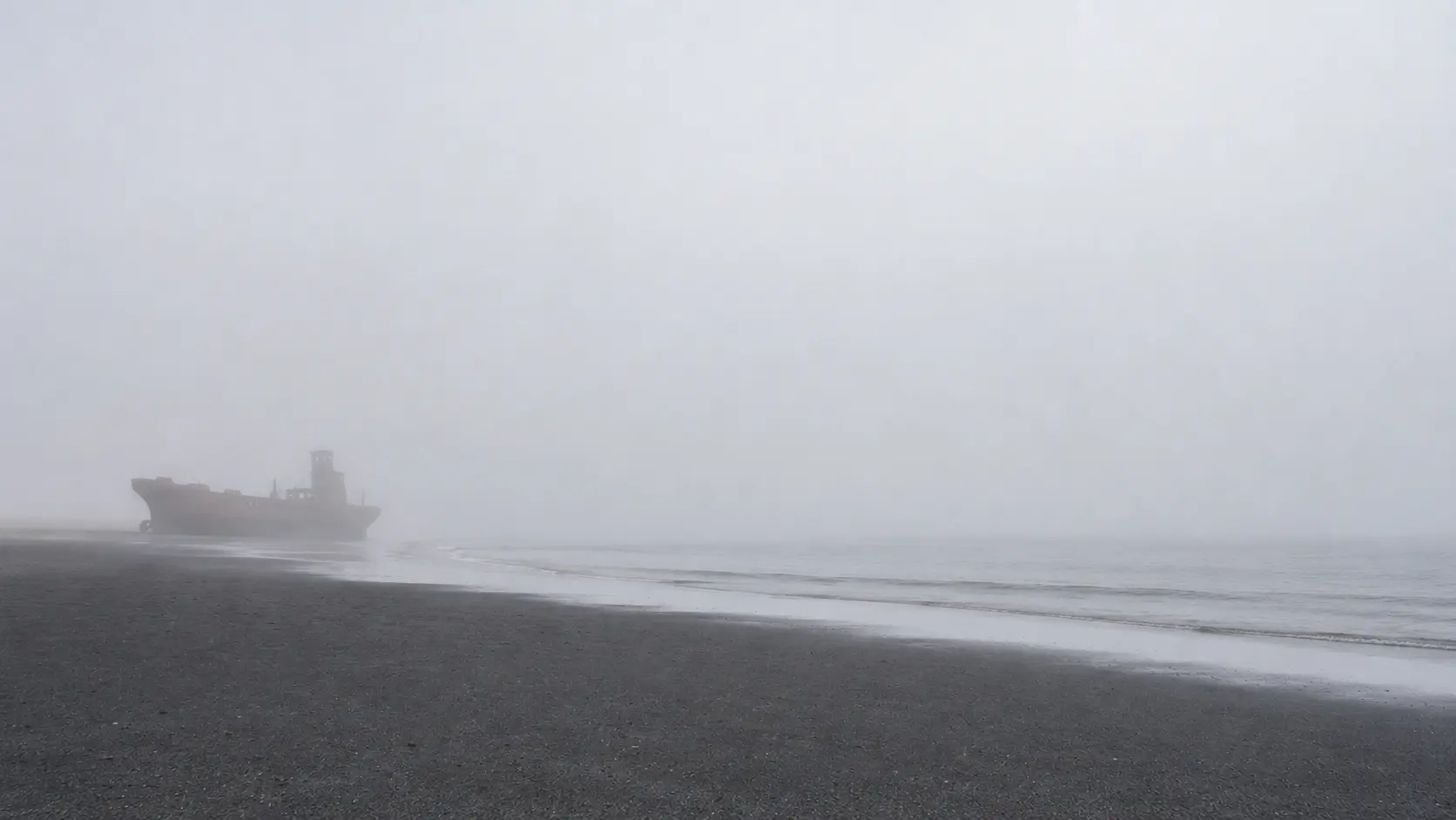 A distant vessel silhouette fading into Skeleton Coast fog