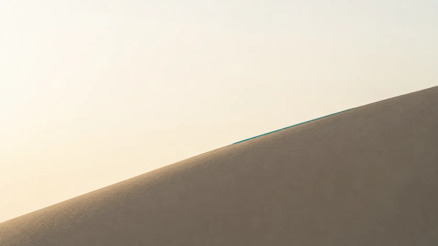 A clean Namib dune ridge marked by one restrained teal line